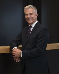Prof. Dr. Henning Werner, Rektor der EBS Universität, steht am Empfangstresen und lächelt freundlich.