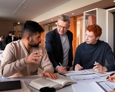 A professor and students of EBS University work together in a workshop