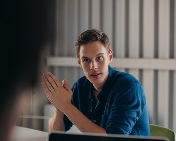 Mann im Meeting am Tisch mit den Handflächen aufeinander