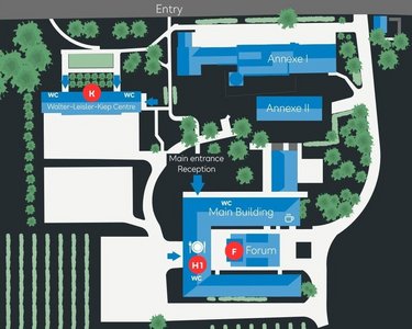 Site plan of an area with various buildings, including the main building, a reception area, and a forum. Surrounded by gardens and vineyards, with marked entrances and pathways.