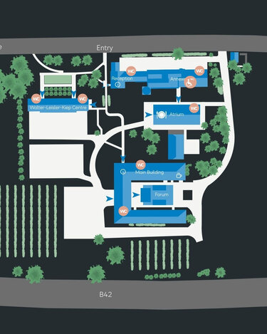 Labeled site map showing the layout of a complex, including buildings such as the Main Building, Forum, and various amenities, with pathways and green spaces indicated.
Map overview of the arrangement of a complex, including buildings like the Main Building, Forum, and various amenities, with pathways and green areas.