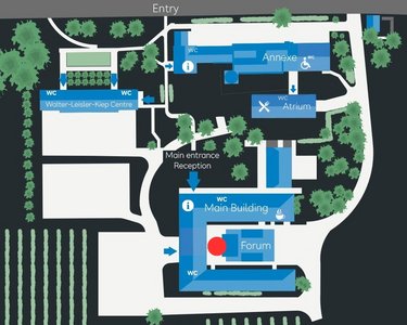 Site plan of an area featuring various buildings, including the main building, the forum, and the reception area. Surrounded by green spaces, trees, and vineyards, with access from Rheingastraße and B42.