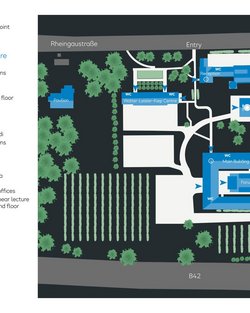 Campus layout featuring various buildings, including a library, lecture halls, and administrative offices, as well as an entrance area and outdoor facilities.