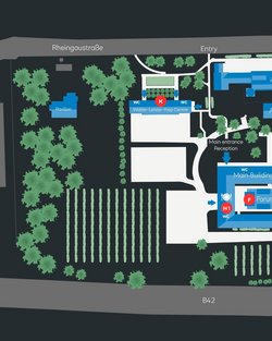 Site plan of an area featuring various buildings, including the main building, reception, and forum, surrounded by green spaces and vineyards. Entrances and pathways are clearly marked.